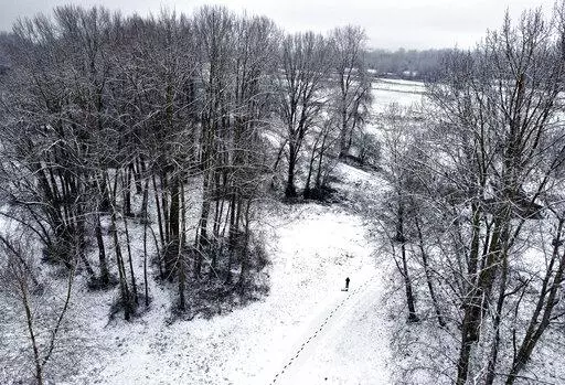 A trail of footprints lead from the parking lot to the water as freshly-fallen snow blankets Frenchman's Bar Regional Park in Vancouver, Wash., on Tuesday, Dec. 28, 2021. The winter storm dropped between 1 and 2 inches of snow on the city. (Amanda Cowan/The Columbian via AP)