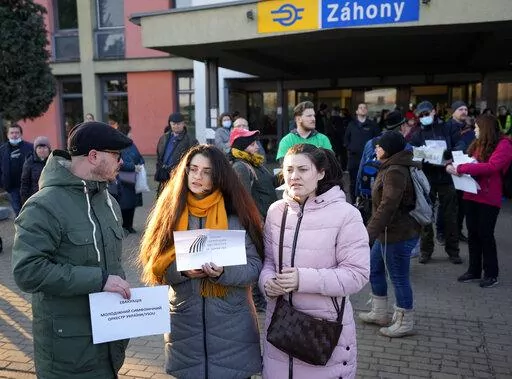 Slovenian volunteer Uros Dokl, left, and violin player Myroslava Sherbina, center, wait for members of the Youth Symphonic Orchestra of Ukraine at the train station in Zahony, Hungary, Sunday, March 6, 2022. When Russia's invasion of Ukraine began and air raid sirens rang out in the embattled region of Donbas, Myroslava Sherbina rushed from her home and into a bomb shelter bringing only two of her possessions: the clothes on her back, and her violin. (AP Photo/Darko Vojinovic)