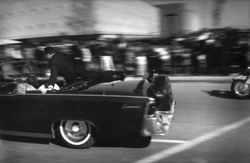 The limousine carrying mortally wounded President John F. Kennedy races toward the hospital seconds after he was shot, Nov. 22, 1963, in Dallas. The 60th anniversary of President Kennedy's assassination, marked on Wednesday, Nov. 22, 2023, finds his family, and the country, at a moment many would not have imagined in JFK's lifetime. (AP Photo/Justin Newman, File)