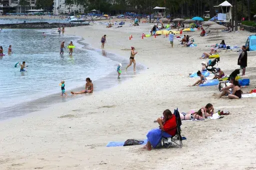 People sit on Waikiki Beach in Honolulu, Aug. 24, 2021. Honolulu police recently got some attention on social media for recommending that beachgoers not leave their valuables unattended and instead put them in a waterproof bag and take them into the ocean. (AP Photo/Caleb Jones, File)