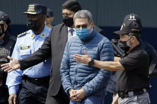 Former Honduran President Juan Orlando Hernandez, second from right, is taken in handcuffs to a waiting aircraft as he is extradited to the United States, at an Air Force base in Tegucigalpa, Honduras, April 21, 2022. Hernández has been convicted in New York, Friday, March 8, of charges that he conspired with drug traffickers, his military and police to enable tons of cocaine to make it unhindered into the United States. (AP Photo/Elmer Martinez, File)