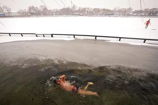 A man swims in the half-frozen water at the Shichahai Lake during a snow fall in Beijing, Sunday, Feb. 13, 2022. According to some of the local residents, swimming in the freezing water leads to health. (AP Photo/Andy Wong)
