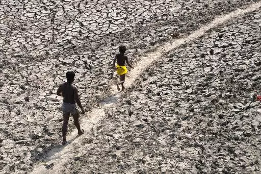 A man and a boy walk across the almost dried up bed of river Yamuna following hot weather in New Delhi, India, Monday, May 2, 2022. According to a report released by the World Meteorological Organization on Monday, May 9, 2022, the world is creeping closer to the warming threshold international agreements are trying to prevent, with nearly a 50-50 chance that Earth will temporarily hit that temperature mark within the next five years. (AP Photo/Manish Swarup, File)