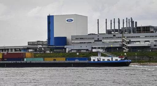 A container ship passes the Ford car plant in Cologne, Germany, May 4, 2020. Ford said that it will cut 3,800 jobs in Europe over the next three years in an effort to streamline its operations as it contends with economic headwinds and increasing competition on electric cars. The automaker said that 2,300 jobs will go in Germany. (AP Photo/Martin Meissner, File)