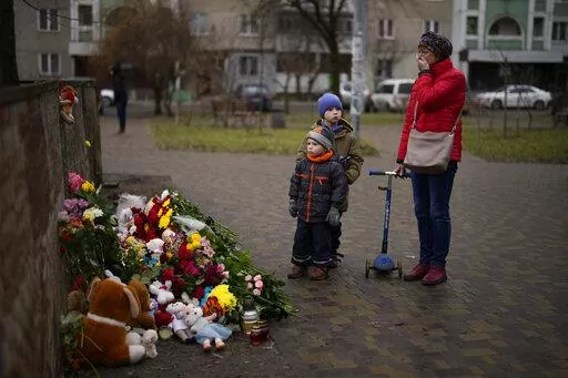 People pay their respects at a makeshift memorial at the scene where a helicopter crashed into civil infrastructure on Wednesday, Jan. 18, in Brovary, on the outskirts of Kyiv, Ukraine, Friday, Jan. 20, 2023. This past week has been an especially tragic one for Ukraine. A barrage of Russian missiles struck an apartment complex in the southeastern city of Dnipro on Jan. 14, and the death toll from that attack rose steadily in the days that followed, with at least 45 civilians killed, including si