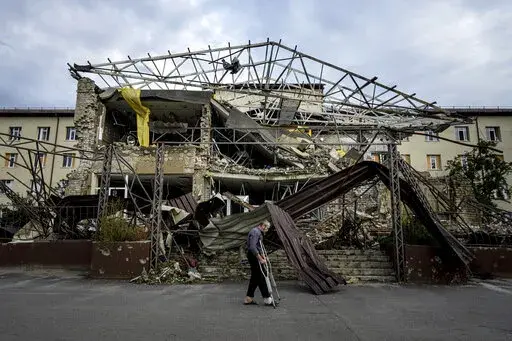 A patient walks past the surgery department which was destroyed after a Russian attack at the hospital in Izium, Ukraine, Saturday, Sept. 17, 2022. Medical staff at the Izium hospital in eastern Ukraine are fighting the memories of six deadly months under Russian occupation. They also are looking darkly ahead at the coming months without electricity. (AP Photo/Evgeniy Maloletka)
