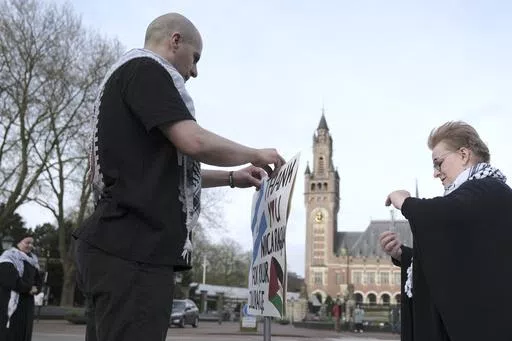 A pro-Palestinian activist works on a protest poster near the International Court of Justice, or World Court, in The Hague, Netherlands, Monday, April 8, 2024, prior to the start of a two days hearing in a case brought by Nicaragua accusing Germany of breaching the genocide convention by providing arms and support to Israel. (AP Photo/Patrick Post)