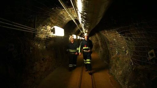 Two researchers walk through an old mining tunnel to what is now the Sanford Underground Research Facility in Lead, S.D., on Dec. 8, 2019. The laboratory houses a dark matter detector.  Scientists have begun a new search for mysterious dark matter in a former gold mine a mile underground. Dark matter makes up the vast majority of the mass of the universe but scientists don't know what it is. (AP Photo/Stephen Groves)