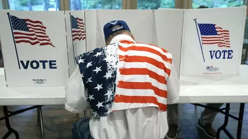 A patriotic voter sits at a voting kiosk and selects his choices in a party primary in Jackson, Miss., Tuesday, Aug. 8, 2023. Super Tuesday put former President Donald Trump within reach of clinching his third consecutive Republican presidential nomination. But it may be Republican voters in Georgia, Hawaii, Mississippi and Washington who put him over the top. President Joe Biden is also competing in presidential contests that day, but the earliest he can clinch his party's nomination is a week 