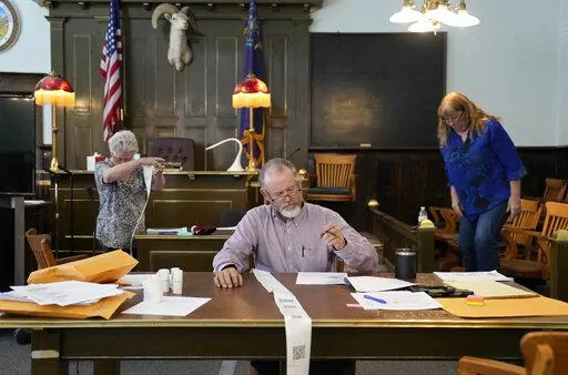 Esmeralda County Commissioner Ralph Keyes, center, works on a hand recount of votes with others, June 24, 2022, in Goldfield, Nev.  An AP survey shows the majority of candidates running this year for the state posts that oversee elections oppose the idea of hand counting ballots, a laborious and error-prone process that has gained favor among Republicans who have been inundated with unfounded voting machine conspiracy theories.  (AP Photo/John Locher, File)