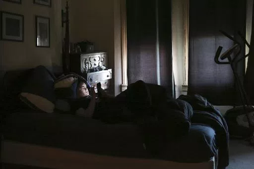 James Walter uses a phone at home in the Queens borough of New York, on April 7, 2021. Sleep scientists long ago established that insufficient sleep is linked with poor health outcomes, anxiety, obesity and several other negative effects. The research is equally conclusive that smartphones are particularly disruptive to the circadian clock that regulates sleep and other hormones. (AP Photo/Jessie Wardarski, File)