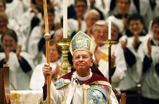FILE - Gene Robinson is applauded after his investiture as the Episcopal Church's bishop of New Hampshire at St. Paul's Church in Concord, N.H., on Sunday, March 7, 2004. In 2008, when Robinson was excluded from a global Anglican gathering because of his sexuality, Desmond Tutu, who died Sunday, Dec. 26, 2021, came to his defense. (AP Photo/Lee Marriner, File)