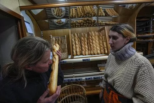 Bakery owner Florence Poirier, LEFT, smells the fresh baguette who comes out of the oven as Mylene Poirier stands next to her at a bakery, in Versailles, west of Paris, Tuesday, Nov. 29, 2022. The humble baguette -- the crunchy ambassador for French baking around the world -- is being added to the U.N.'s list of intangible cultural heritage as a cherished tradition to be preserved by humanity. UNESCO experts gathering Wednesday Nov. 30, 2022 in Morocco decided that the simple French flute deserv
