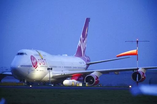 Virgin Atlantic Cosmic Girl, a repurposed Virgin Atlantic Boeing 747 aircraft carrying a rocket, is parked at Spaceport Cornwall, at Cornwall Airport in Newquay, England, Monday, Jan. 9, 2023. Engineers are making final preparations for the first satellite launch from the U.K. later Monday, when a repurposed passenger plane is expected to release a Virgin Orbit rocket carrying several small satellites into space. (Ben Birchall/PA via AP)