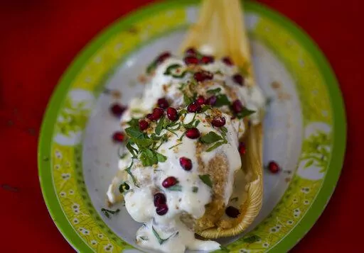 A Chiles en Nogada style tamal is displayed during the tamales fair at the Ixtapalapa neighborhood of Mexico City, Friday, Jan. 27, 2023. Chiles en nogada is a Mexican dish of poblano chiles stuffed with picadillo topped with a walnut-based cream sauce called nogada, pomegranate seeds and parsley, and it is typically served at room temperature. It is widely considered a national dish of Mexico. (AP Photo/Fernando Llano)