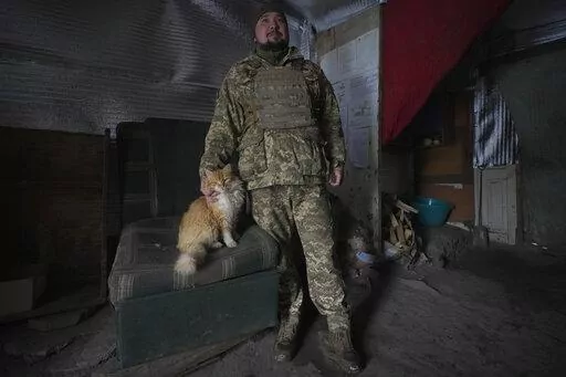 An Ukrainian serviceman pats Vasiliy the cat at an advanced position on the front line in the Luhansk area, eastern Ukraine, Thursday, Jan. 27, 2022. The U.S. rejection of Russia's main demands to resolve the crisis over Ukraine left "little ground for optimism," the Kremlin said Thursday, but added that dialogue was still possible. (AP Photo/Vadim Ghirda)