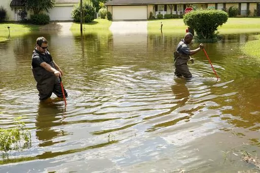 Hinds County, Miss., Emergency Management Operations Deputy Director Tracy Funches, right, and Operations Coordinator Luke Chennault, left, wade through floodwaters in northeast Jackson, Miss., Aug. 29, 2022, as they check water levels. Flooding affected a number of neighborhoods that are near the Pearl River. Environmental groups in Mississippi presented findings Wednesday, Dec. 6, 2023, from the U.S. Army Corps of Engineers showing a long-debated flood control project along the Pearl River wou