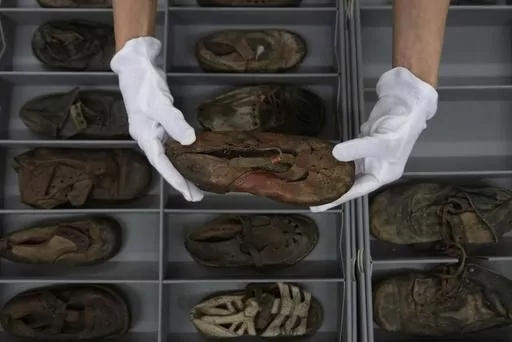 Elzbieta Cajzer, head of the museum's collections department, shows a collection of shoes that belonged to child victims of the former Nazi German death camp Auschwitz-Birkenau at the conservation laboratory on the grounds of the camp in Oswiecim, Poland, Wednesday, May 10, 2023. A two-year effort has been launched in 2023 to preserve 8,000 children’s shoes at the former concentration and extermination camp where German forces murdered 1.1 million people during World War II. (AP Photo/Michal D