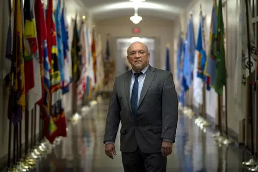 Tracy Toulou, the outgoing Director of the Office of Tribal Justice, stands in a hallway lined with flags of tribal nations at the Department of Justice, Thursday, March 14, 2024, in Washington. For more than two decades, Toulou has confronted the serious public safety challenges facing Indian Country by working to expand the power of tribal justice systems. Today, tribal law enforcement finally has a seat at the table when federal authorities coordinate with state and local police, according to