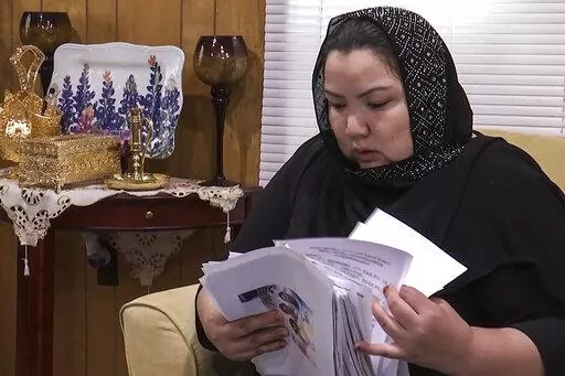 In this image from video, Zumret Dawut, a Uighur from China's western Xinjiang region who forcibly sterilized for having a third child after being released from a Xinjiang detention camp, looks at documents at her home in Woodbridge, Va., on Monday, June 15, 2020. For Dawut and other camp survivors who spoke out, the U.N.'s report on the mass detentions and other rights abuses against Uyghurs and other mostly Muslim ethnic groups in Xinjiang was the culmination of years of advocacy, and a much-w