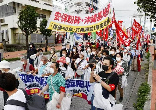 Protesters march, opposing to the ceremony marking the 50th anniversary of its return to Japan after 27 years of American rule on May 15, 1972,  in Ginowan, Okinawa, Sunday, May 15, 2022. Protesters staged a rally demanding a speedier reduction of U.S. military forces.(Kyodo News via AP)