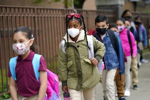 Students line up to enter Christa McAuliffe School in Jersey City, N.J., April 29, 2021. New Jersey Gov. Phil Murphy will end a statewide mask mandate to protect against COVID-19 in schools and child care centers, his office said Monday, Feb 7, 2022. (AP Photo/Seth Wenig, File)