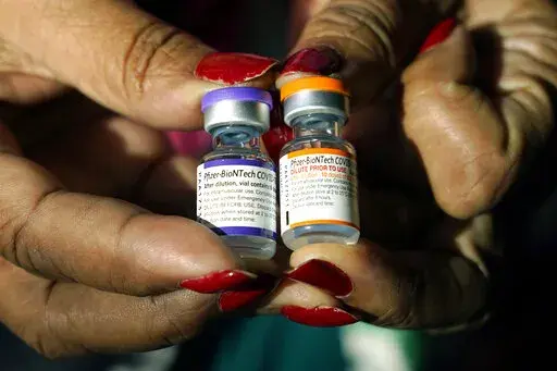 A nurse holds a vial of the Pfizer COVID-19 vaccine for children ages 5 to 11, right, and a vial of the vaccine for adults, which has a different colored label, at a vaccination station in Jackson, Miss., Tuesday, Feb. 8, 2022. U.S. regulators authorized a COVID-19 booster shot for healthy 5- to 11-year-olds on Tuesday, May 17, 2022, hoping an extra vaccine dose will enhance their protection as infections once again are on the rise. (AP Photo/Rogelio V. Solis, File)