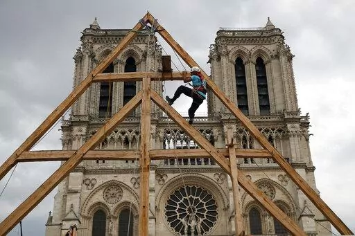 Charles, one of the carpenters puts the skills of their medieval colleagues on show on the plaza in front of Notre Dame Cathedral in Paris, France, Saturday, Sept. 19, 2020. France's Notre Dame Cathedral's reconstruction is progressing enough to allow its reopening to visitors and masses at the end of next year, less than six years after the after the shocking fire that tore through its roof, French officials said as an exhibit pays tribute to hundreds of artisans working on it. (AP Photo/Franco
