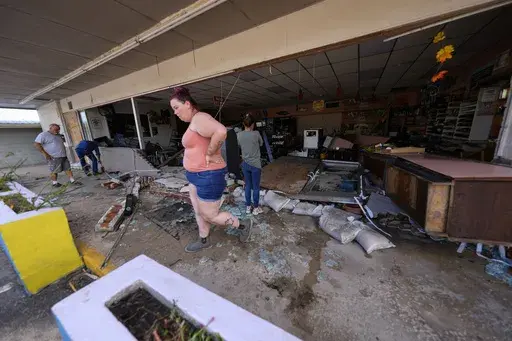 Kegan Ward, assistant manager of Swami Spirits, walks through debris of the damaged store in the aftermath of Hurricane Helene, in Cedar Key, Fla., on Sept. 27, 2024. (AP Photo/Gerald Herbert, File)