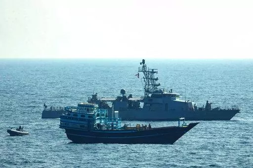 This photo released by the U.S. Navy, shows U.S. service members conduct a boarding on a stateless fishing vessel transiting international waters in the Gulf of Oman as a rigid-hull inflatable boat and patrol coastal ship USS Chinook (PC 9) sail nearby, Tuesday, Jan. 18, 2022. The U.S. Navy announced Sunday, Jan. 23 that it seized the boat in the Gulf of Oman carrying fertilizer used to make explosives that was caught last year smuggling weapons to Yemen. (U.S. Navy via AP)