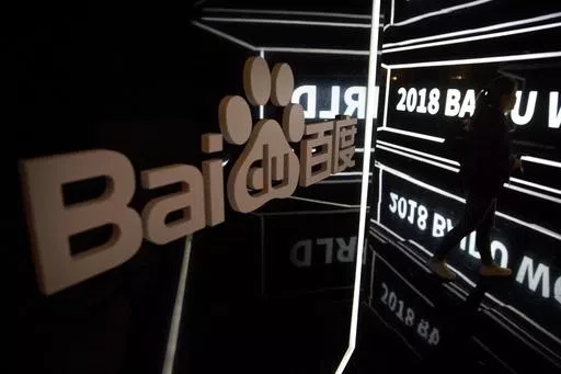 An attendee walks past a display at the Baidu World conference in Beijing, on Nov. 1, 2018. A top public relations executive from Chinese technology firm Baidu apologized Thursday, May 9, 2024, after she made comments in a series of videos that critics said glorified a culture of overwork. (AP Photo/Mark Schiefelbein, File)