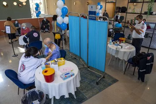 A man receives his fourth dose of the coronavirus vaccine in a private nursing home in Petah Tikva, Israel, Tuesday, Jan. 4, 2022. Even in relatively small, wealthy Israel, an early global leader against the coronavirus pandemic, the omicron variant is outpacing the government's ability to make and execute clear pandemic public policy. What once was a straightforward regimen of vaccines, testing, contact tracing and distancing for the nation of 9.3 million has splintered into a zigzag of rules t