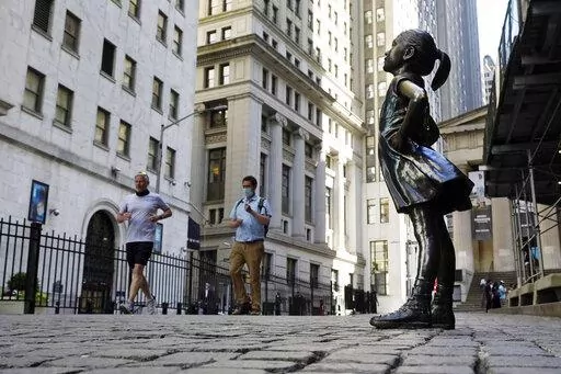 In this June 16, 2021, photo, the "Fearless Girl" statue faces the New York Stock Exchange. The 4-foot bronze "Fearless Girl" statue that was installed opposite New York City's Charging Bull in 2017 will remain in its current spot opposite the New York Stock Exchange at least until early 2023 while city officials wrestle with a permanent disposition for the popular symbol of female empowerment, a city board decided Monday, April 11, 2022. (AP Photo/Richard Drew, File)