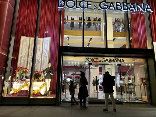People stand outside the Dolce & Gabbana store on Fifth Avenue, Nov. 21, 2021, in New York. (AP Photo/Pamela Hassell, File)
