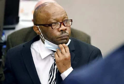 Defendant Billy Chemirmir lowers his mask as a state witness is asked to identify him during his murder trial at the Frank Crowley Courts Building in Dallas, Nov. 17, 2021. The retrial of the man charged with killing 18 older women in the Dallas area over a two-year span is set to begin Monday, April 25, 2022 after the first jury to hear a case against him deadlocked. Chemirmir faces life in prison without parole if he’s convicted of capital murder in the smothering of 81-year-old Lu Thi Harri