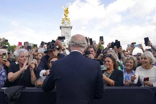 Britain's King Charles III, back to camera, greets well-wishers as he walks by the gates of Buckingham Palace following Thursday's death of Queen Elizabeth II, in London, Friday, Sept. 9, 2022. King Charles III, who spent much of his 73 years preparing for the role, planned to meet with the prime minister and address a nation grieving the only British monarch most of the world had known. He takes the throne in an era of uncertainty for both his country and the monarchy itself. (Yui Mok/Pool Phot