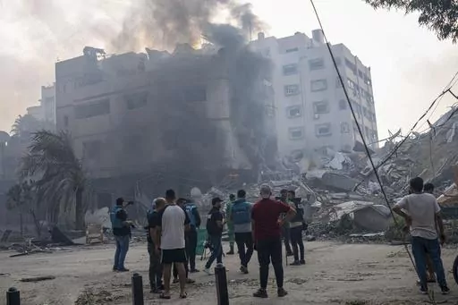 Journalists observe as Palestinians inspect the rubble of a building after it was struck by an Israeli airstrike, in Gaza City, Sunday, Oct. 8, 2023. Journalists reporting in Gaza need to worry about basic survival for themselves and their families in addition to getting out the story of a besieged population. (AP Photo/Fatima Shbair, File)