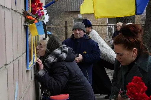 Anna Levchenko, 81, kisses the picture of her grandson Andrii Matviichuk, during a gathering to mark the first anniversary of the death of eight men killed by Russian forces in Bucha, Ukraine, Saturday, March 4, 2023. The eight had set up a roadblock on a road in the town in an attempt to prevent Russian troops from advancing, as they swept towards the Ukrainian capital at the start of their invasion. (AP Photo/Thibault Camus)