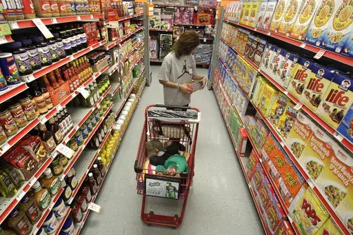 A woman looks at products in the aisle of a store as her daughter naps in the shopping cart in Waco, Texas, on Dec. 14, 2010. (AP Photo/Tony Gutierrez, File)